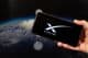 Main d'un homme tenant un smartphone avec un logo Starlink dans la main droite.
