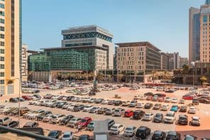 Parking extérieur avec des centaines de voitures près d'un hôtel et d'un centre d'affaires à Dubaï.