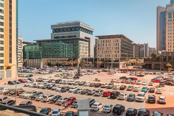 Parking extérieur avec des centaines de voitures près d'un hôtel et d'un centre d'affaires à Dubaï.