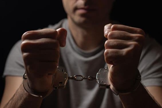 Mains menottées devant soi.