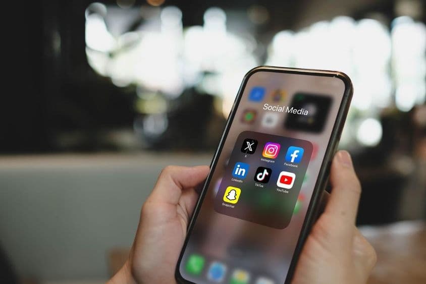Écran iPhone 15 Pro avec icônes d'applications de réseaux sociaux.