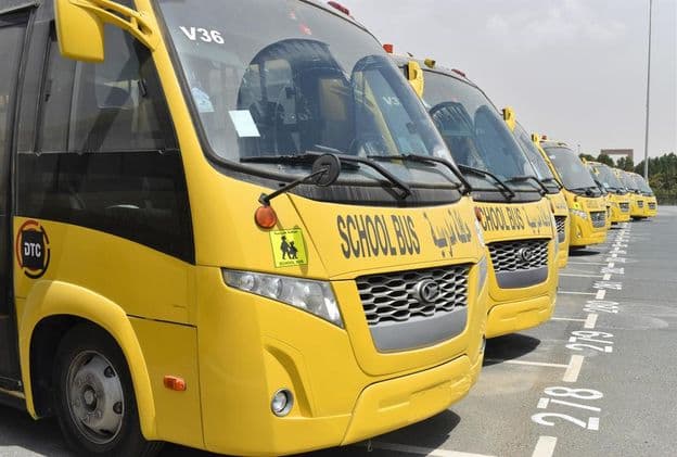 Plusieurs bus scolaires jaunes alignés dans un parking à Dubaï.
