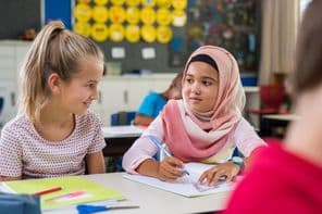 Écolière musulmane assise près d'une camarade de classe pendant un cours.