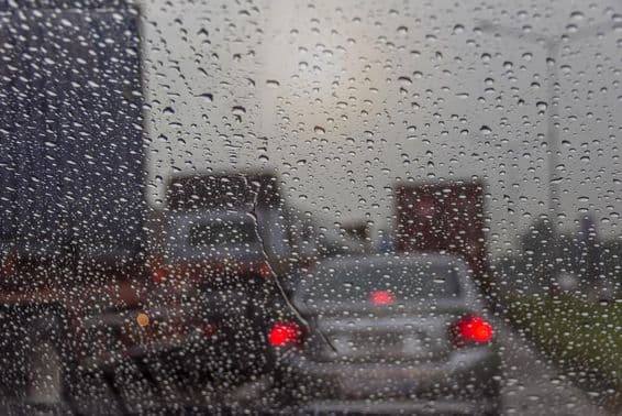 Pluie vue à travers une vitre de voiture.