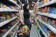 Une jeune femme arabe regarde des snacks dans un supermarché.