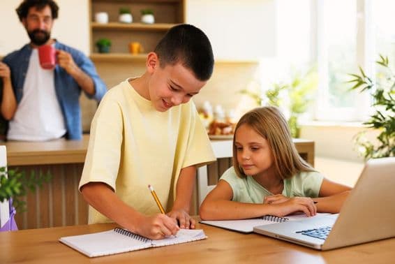 Frères et sœurs faisant leurs devoirs à la maison avec des ordinateurs portables et des cahiers