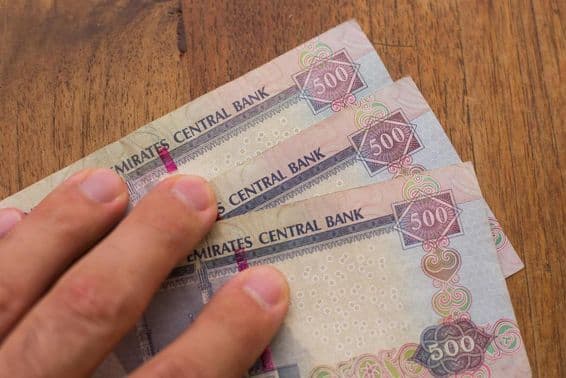 Personnes tenant la monnaie des Émirats Arabes Unis