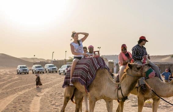 Touristes montant à dos de chameau dans le désert de Dubaï