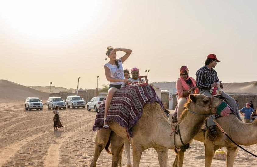 Touristes montant à dos de chameau dans le désert de Dubaï