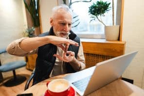 Un homme plus âgé avec une barbe parlant en langue des signes lors d'un appel vidéo.