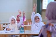 Des élèves musulmans levant la main pour répondre aux questions des enseignants.