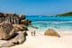 Deux voyageurs marchant sur les sables blancs et doux de la plage d'Anse Cocos aux Seychelles.