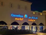 Logo éclairé du marché Carrefour avec le nom de marque en arabe