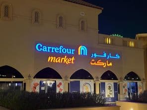 Logo éclairé du marché Carrefour avec le nom de marque en arabe