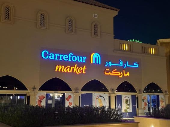 Logo éclairé du marché Carrefour avec le nom de marque en arabe