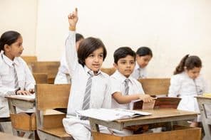 Un enfant d'école indien heureux levant la main