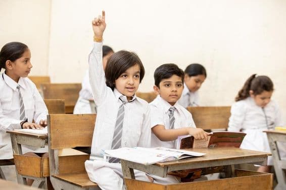 Un enfant d'école indien heureux levant la main