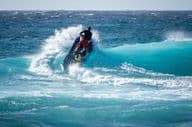 Jetski frappe l'eau au-dessus d'une vague déferlante