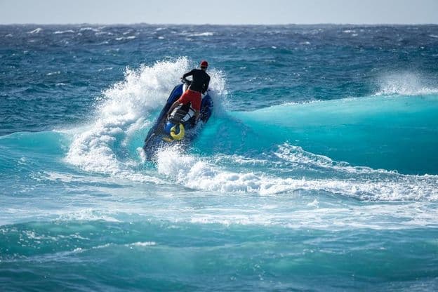 Jetski frappe l'eau au-dessus d'une vague déferlante
