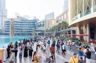Une foule diverse de touristes et de locaux marche le long de la promenade animée devant le Dubai Mall.