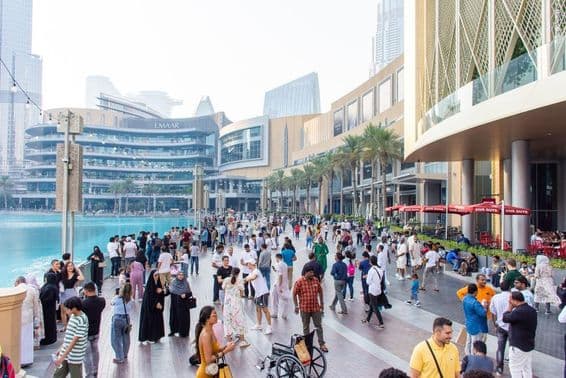 Une foule diverse de touristes et de locaux marche le long de la promenade animée devant le Dubai Mall.